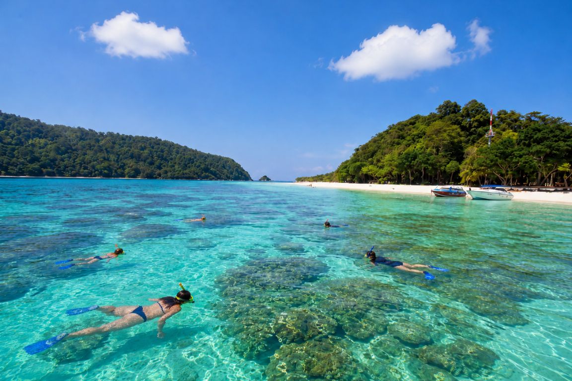 Travelers snorkeling above vibrant coral reefs in the crystal-clear waters of Koh Rok during a Krabi Boat Tours island-hopping adventure