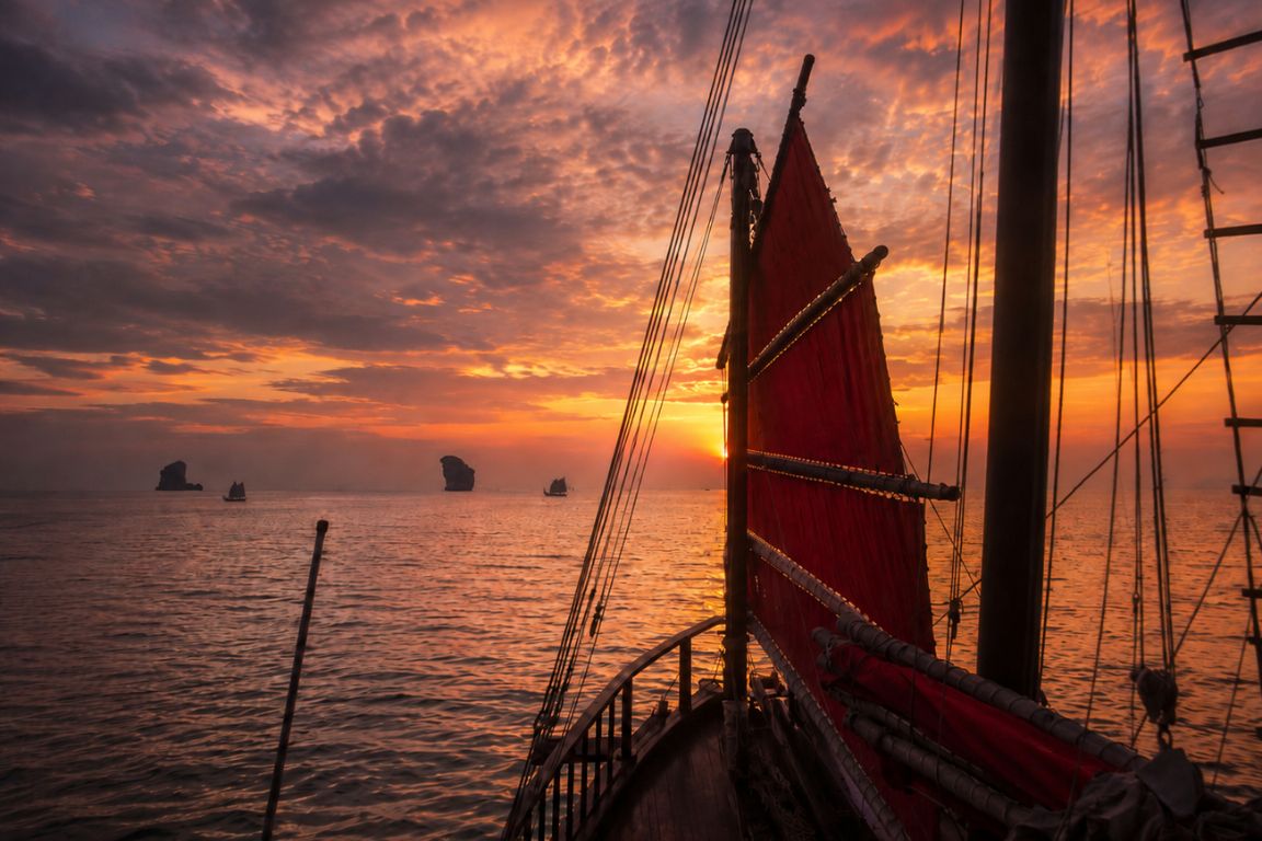 Scenic sunset cruise in Krabi featuring dramatic skies, island silhouettes, and traditional sailing boats during a Krabi Boat Tours tour